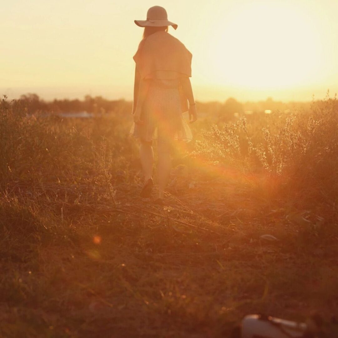 qtq80-xJ0FZD A person in a field with the sun setting